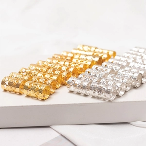 Carved hollow metal hair rings for dreadlocks in gold and silver finish on display