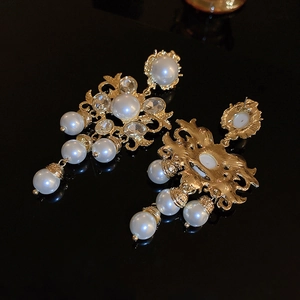 Détail de boucles d'oreilles baroques avec perles, cristaux et fleurs dorées