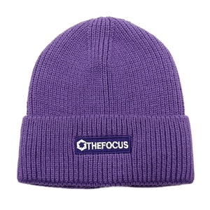 Detail view of purple ribbed knit beanie featuring an embroidered THE FOCUS logo patch