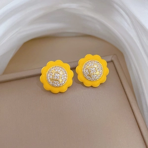 Close-up of yellow sunflower stud earrings with gold finish and sparkling crystal center