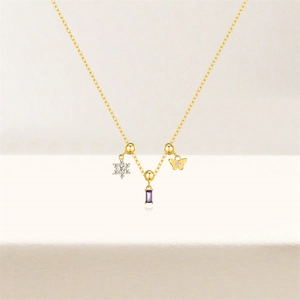 Detail view of gold necklace with purple zircon stone, snowflake and butterfly charms