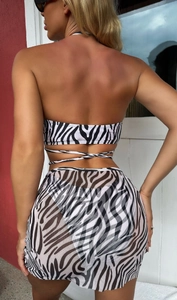 Rear view of zebra print bikini top and sheer mesh skirt set against a red wall