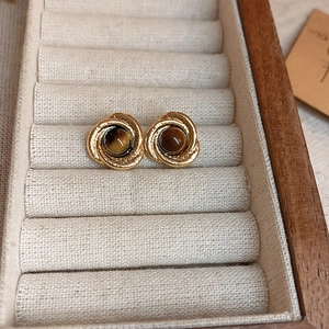 Macro shot of retro gold earrings with round tiger eye stone in a beige velvet jewelry box
