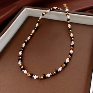 Gros plan de perles d'œil de tigre et de nacre sur un collier de luxe dans un plateau