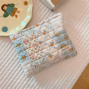 Detailed macro of floral quilted cotton pouch with simple wish brand label on soft fabric
