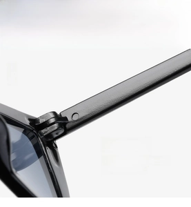 Detailed macro view of the durable hinge design on high-gloss black cat eye sunglasses