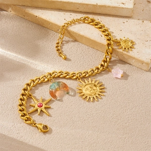 18K gold plated stainless steel sun and moon charm bracelet on beige stone background