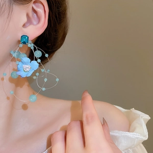 Detail of long fringe glass earrings with light blue fabric flowers and crystals