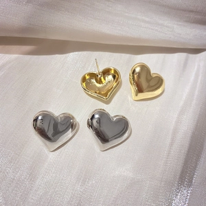 Boucles d'oreilles cœur polies en finition or et argent sur fond de soie blanche