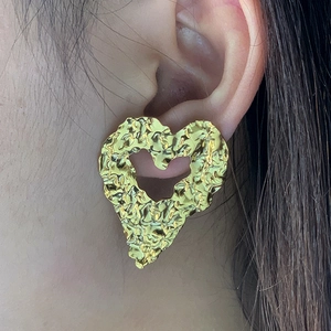 Gros plan d'une boucle d'oreille cœur en acier inoxydable doré avec texture martelée fine