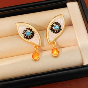 Detail of vintage enamel evil eye earrings with heart blue stone and orange water drop