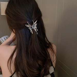 Detailed view of a silver liquid metal butterfly hair claw clip on dark brown hair