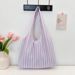 Pink and blue striped canvas tote bag hanging in a cozy, minimalist room decor scene