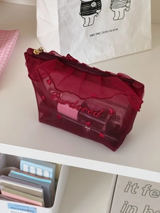 Detail of burgundy mesh cosmetic bag featuring elegant ruffles and heart embroidery