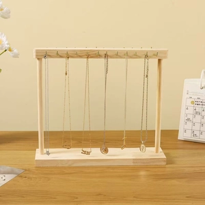 Natural wood necklace display stand with metal hooks and jewelry on a wooden base