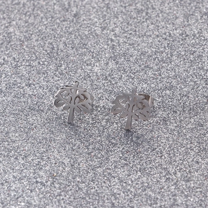 Macro detail of silver stainless steel tree of life stud earrings on a glitter background