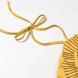 Detailed macro view of yellow satin halter strap with handcrafted metallic floral beadwork