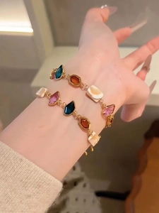 Detail of stacked colorful geometric gemstone bracelets in gold plating on wrist