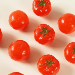 Realistic mini PVC cherry tomatoes with green stems displayed on a beige background