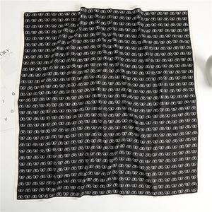 Detailed close-up of a 90cm black silk scarf with an elegant white butterfly pattern
