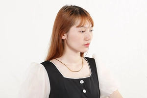 Gros plan d'un collier cœur doré minimaliste porté par un mannequin sur fond blanc épuré