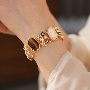 Detail of vintage gold bracelet with cameo portrait, tiger eye stone, and enamel flowers