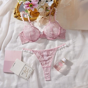 Detailed view of pink floral lace lingerie set with embroidery on white satin background
