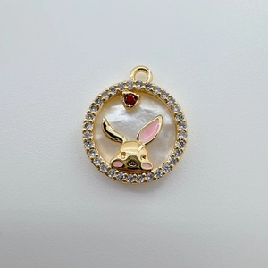 Macro view of gold rabbit charm with white pearl shell and zircon stones inlay