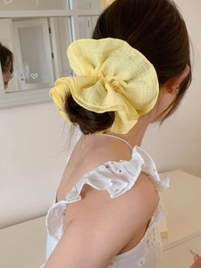 Détail d'un grand chouchou jaune en gaze transparente sur un chignon classique