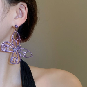Detailed view of luxury purple hollow butterfly earring with zircon stones on a model