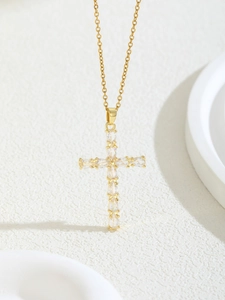 Close-up of golden cross necklace pendant with clear zircon stones in claw setting