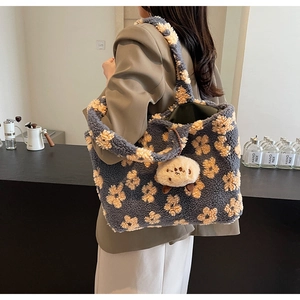 Detail of blue plush tote bag with flower patterns and a cute charm on shoulder