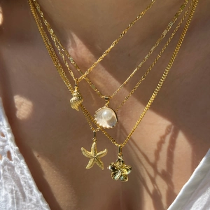 Layered gold necklace featuring sea shell, starfish, and pearl charms for a summer look