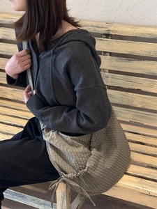 Side view of a large khaki checkered nylon croissant bag worn by a model on a bench