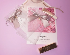 Detail of pink organza drawstring bags featuring ribbon bows and elegant pearl charms