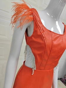 Détail de la robe orange en similicuir avec plumes et découpes à franges en strass