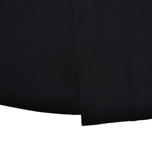 Détail de la texture du tissu tissé et de la fente latérale sur cette robe longue noire