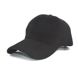 Detail of black knit baseball cap featuring embossed M letter jacquard texture and curved brim