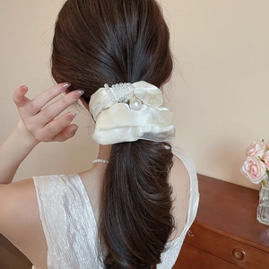 Detailed shot of cream satin scrunchie with large pearls and crystal bead accents