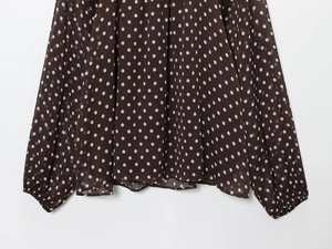 Detailed view of dark brown chiffon blouse fabric with white polka dots and drapes