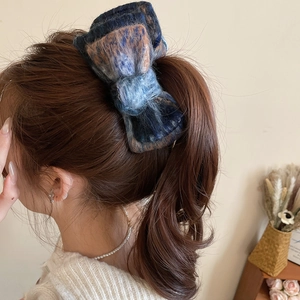 Close-up of blue and brown plaid flocking bow hair clip on model's high ponytail