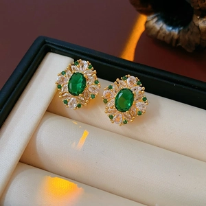 Détail de boucles d'oreilles dorées avec pierres vertes dans un écrin à bijoux