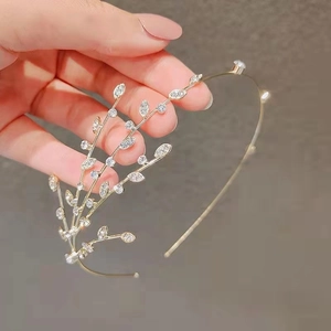 Close-up of golden headband featuring crystal leaves and berries held by hand