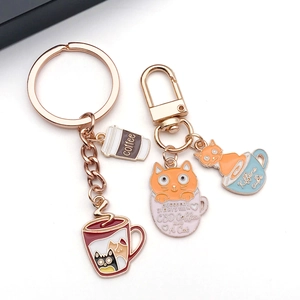 Detailed view of enamel cat and coffee cup charms with polished rose gold lobster clasp