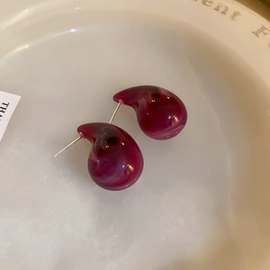 Detail view of purple marble texture resin earrings on a minimalist ceramic dish