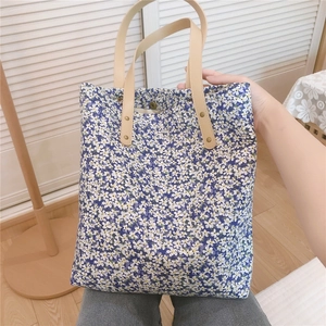 Detail of floral tote bag with blue patterns, faux leather handles and magnetic snap