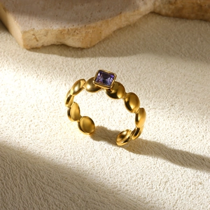 Macro shot of an adjustable gold ring featuring a purple square gemstone and circle band