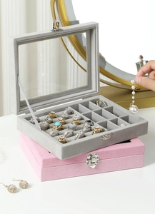 Detail of velvet jewelry box with glass window and ring slots in pink and grey
