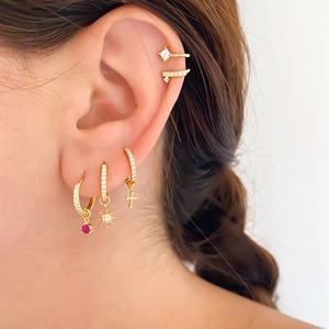 Close-up of gold flower and sunburst ear cuff set with rhinestones on model ear