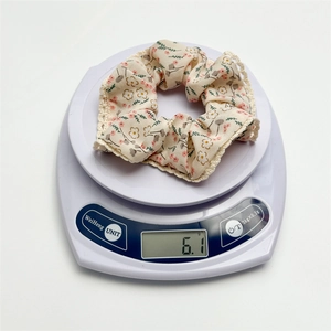 Floral fabric scrunchie with lace edge on a digital scale weighing 6.1g